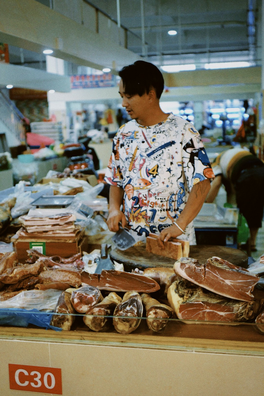 man in blue and white floral shirt standing in front of food display