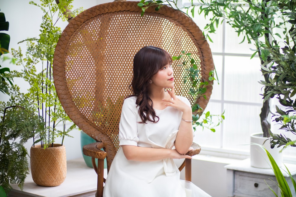 woman in white dress sitting on brown wicker chair