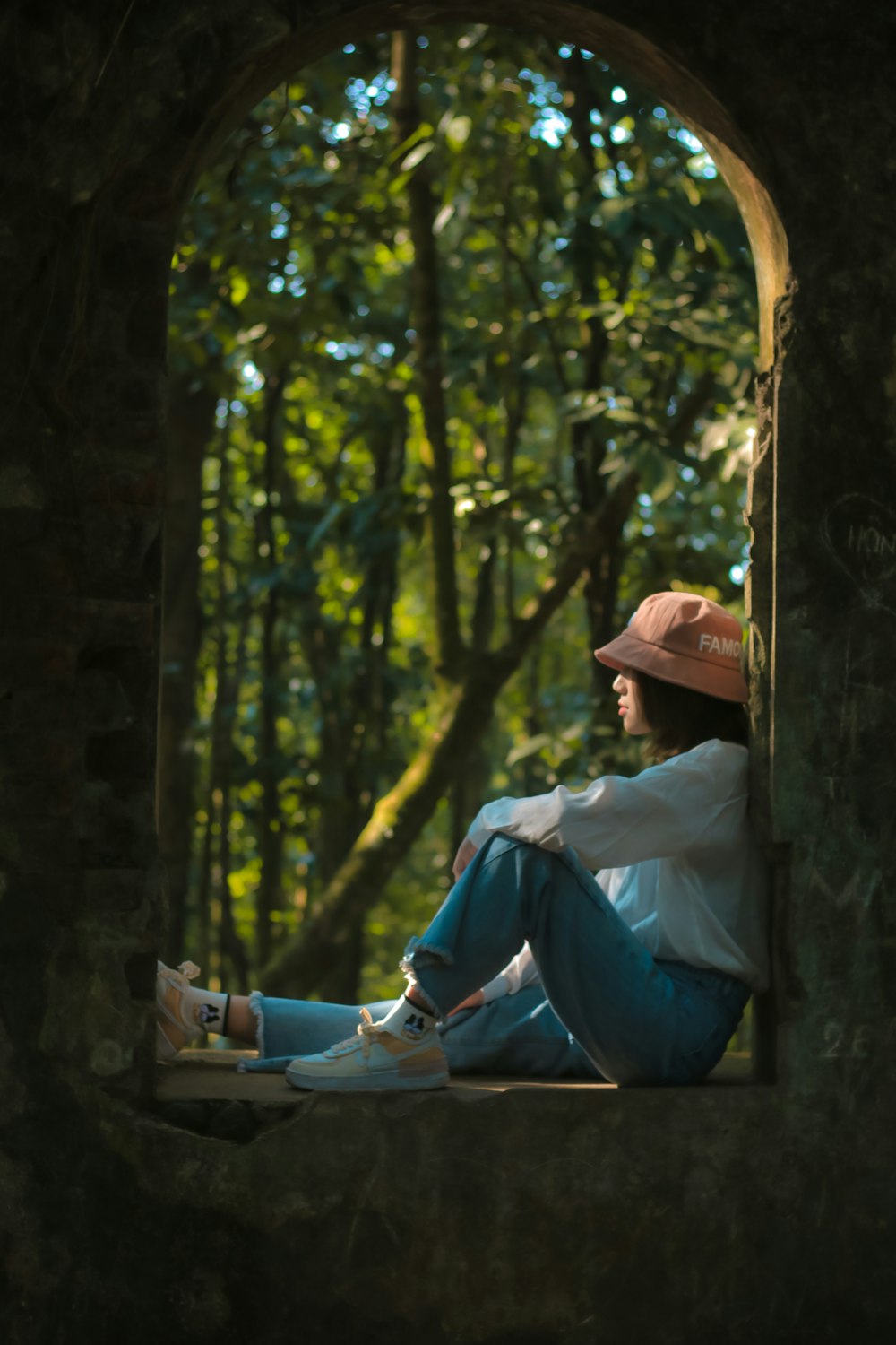 man in blue long sleeve shirt and blue denim jeans sitting on brown wooden post during