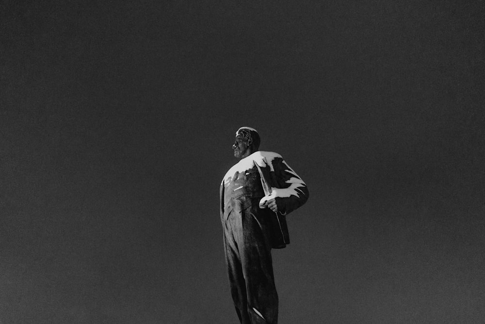 man in black suit jacket and pants standing on black background