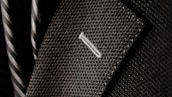 A close-up of a textured suit lapel with detailed stitching, accompanied by a patterned tie in the background.