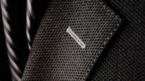 A close-up of a textured suit lapel with detailed stitching, accompanied by a patterned tie in the background.