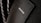 A close-up of a textured suit lapel with detailed stitching, accompanied by a patterned tie in the background.