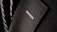 A close-up of a textured suit lapel with detailed stitching, accompanied by a patterned tie in the background.