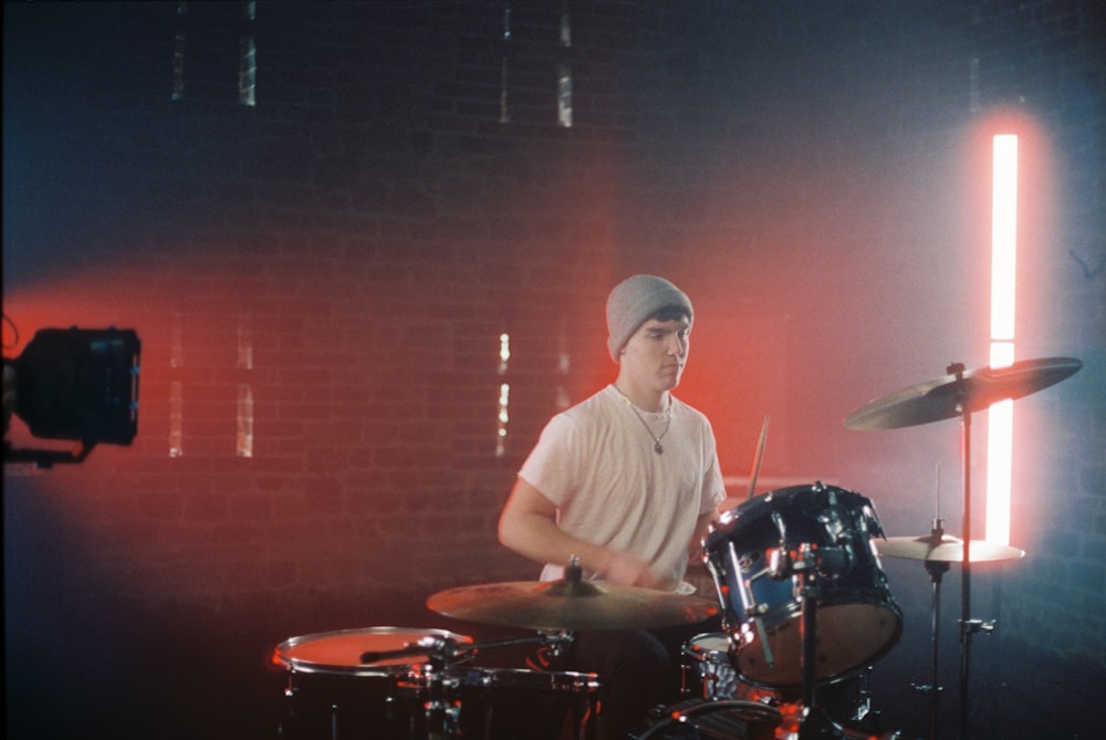 man in white crew neck t-shirt playing drum set