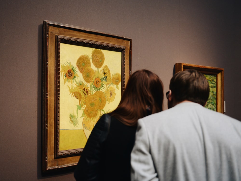 hombre y mujer de pie cerca de la pintura de girasoles