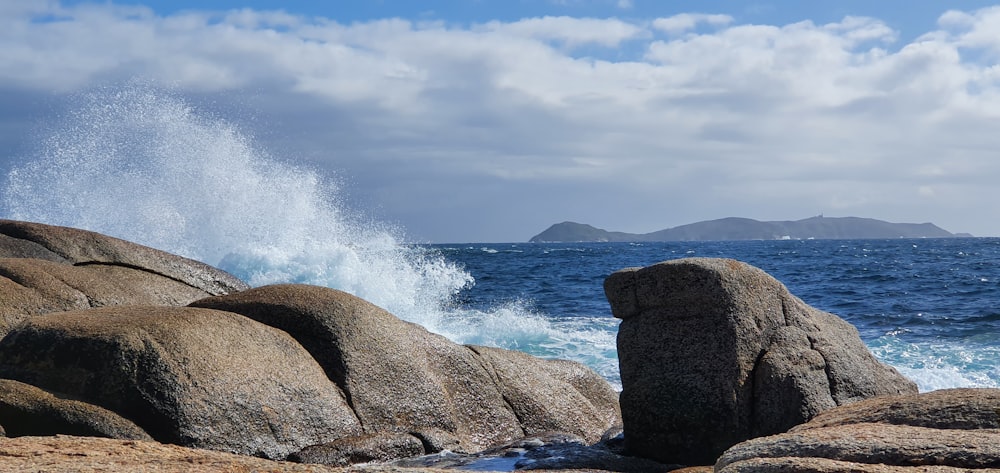 brown rock formation on sea under white clouds during daytime