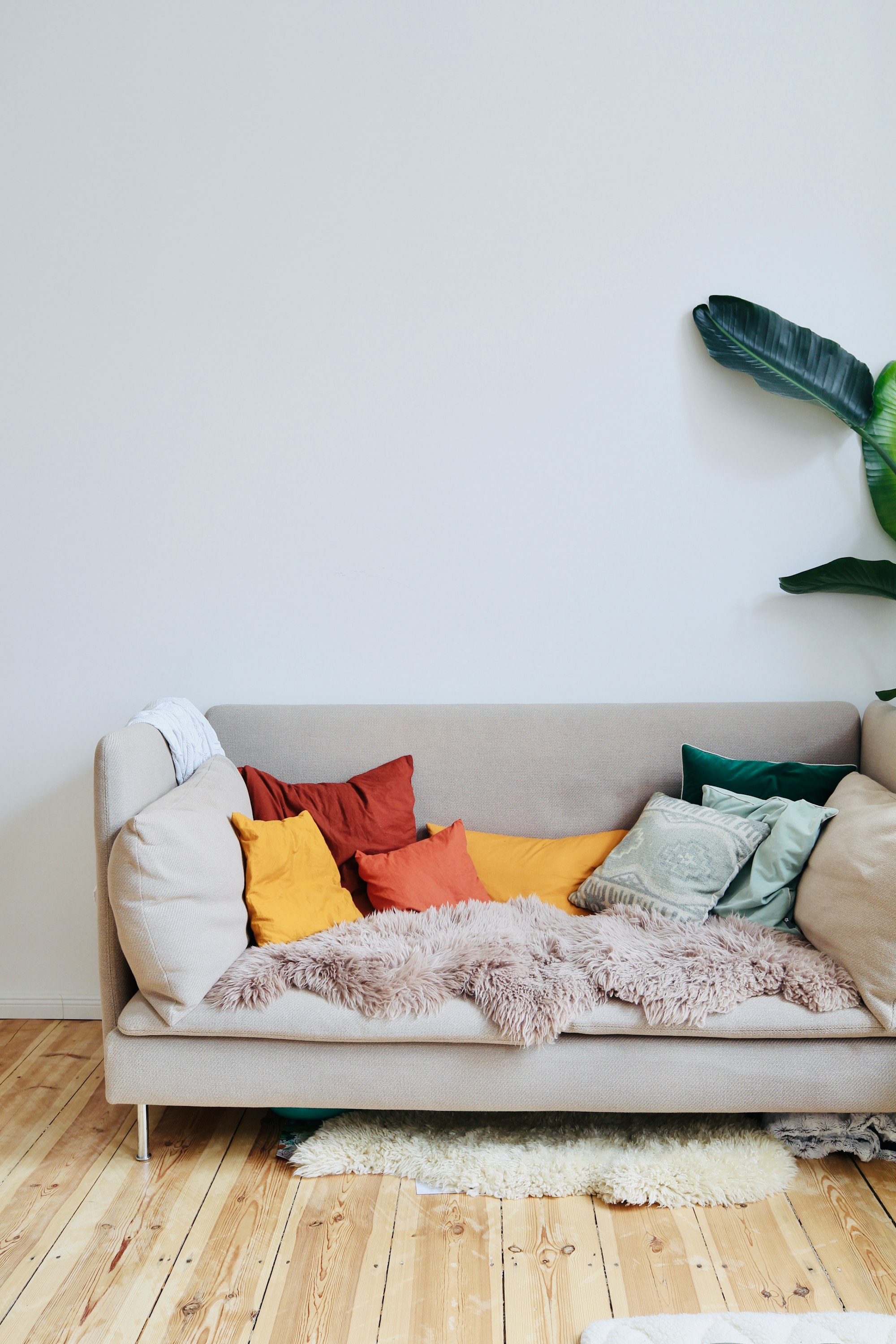 Living room in altbau in Berlin, Germany. Cosy couch and wooden floor with colorful cushions. Available for rental as a film location on beazy.co