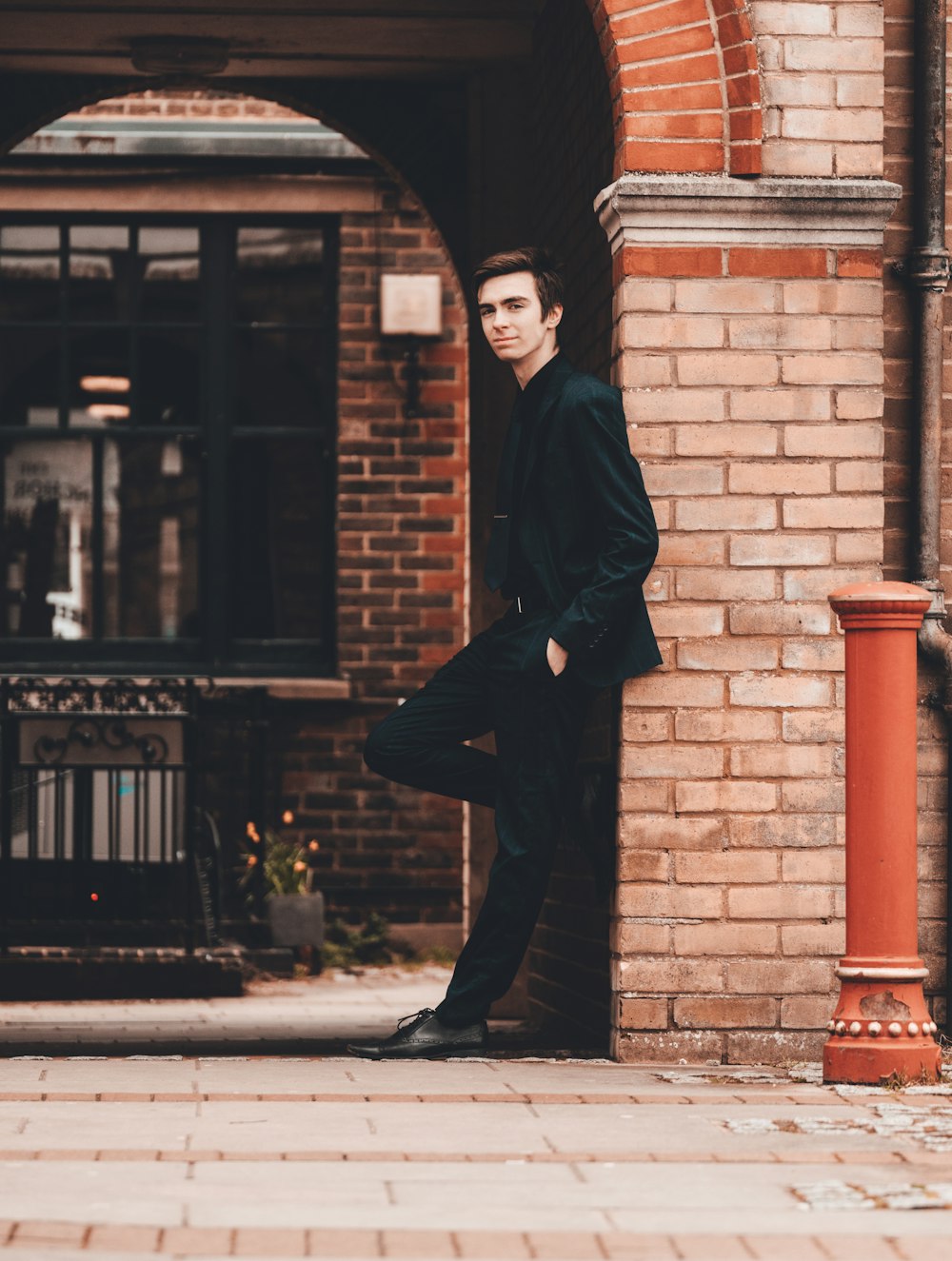 man in black coat standing near brown brick building during daytime