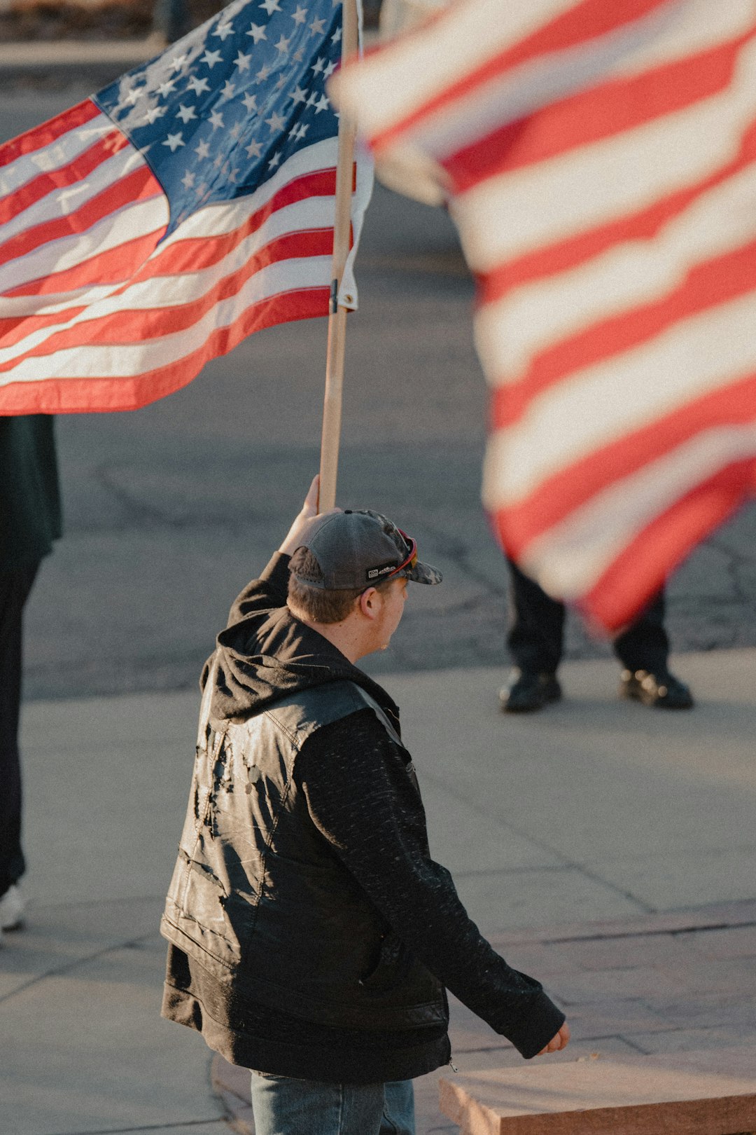 man in black jacket holding us a flag