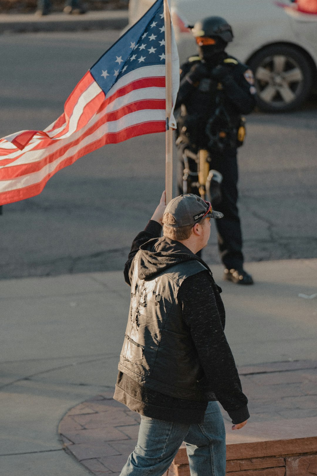 man in black jacket holding flag of us a during daytime