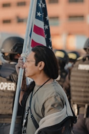A group of diverse Americans standing united, holding a flag, symbolizing resistance and protection of freedoms.