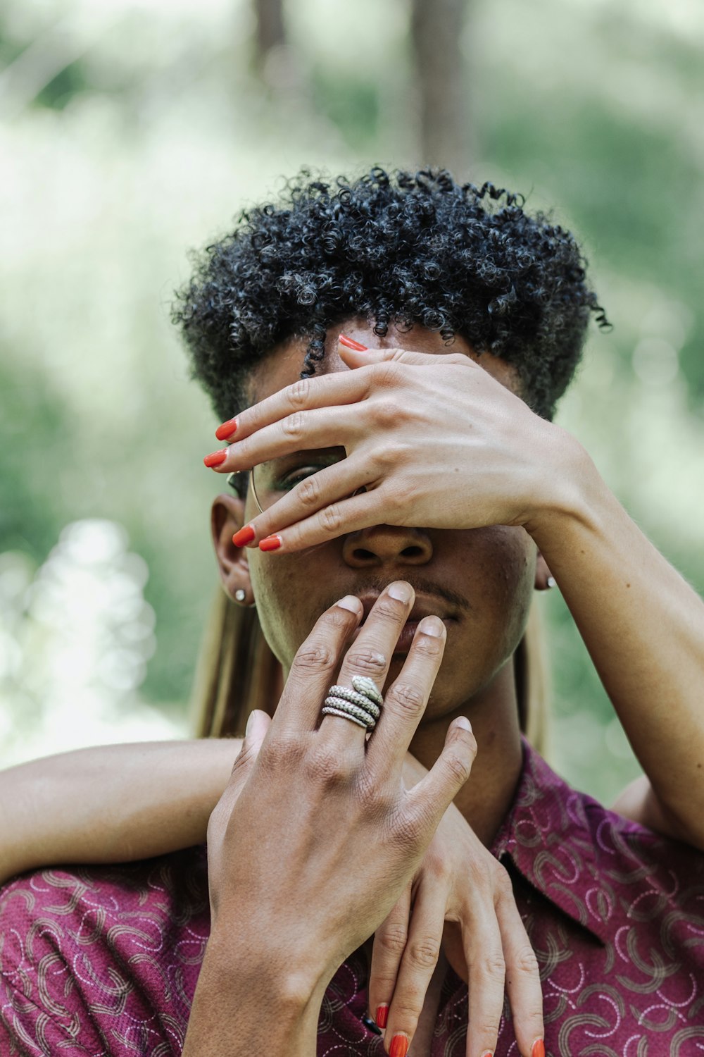 man in purple shirt covering face with both hands