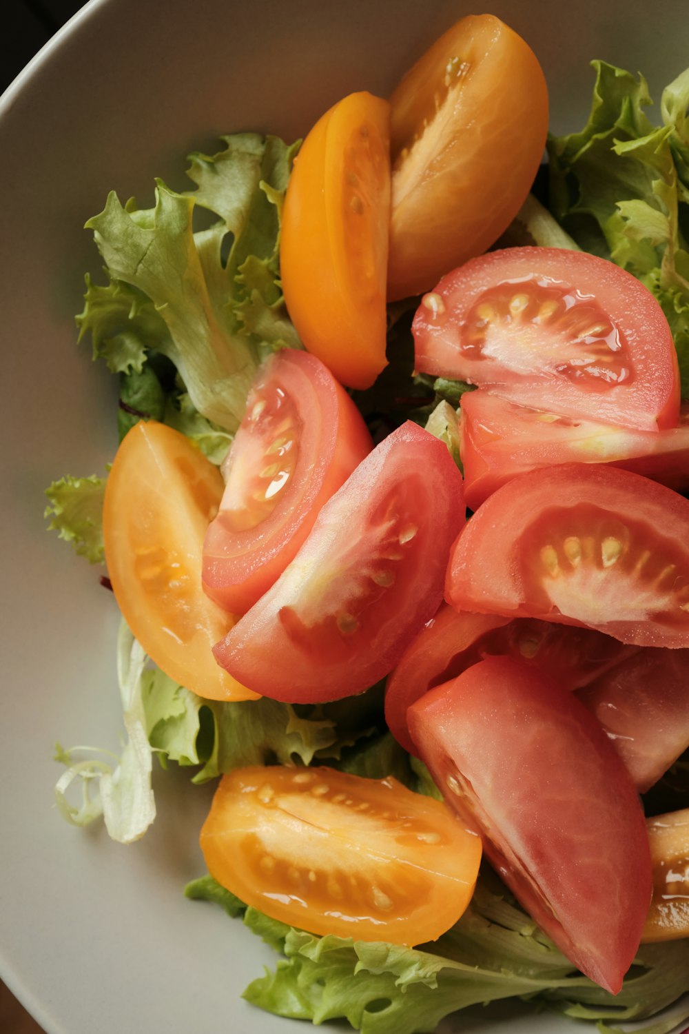 in Scheiben geschnittene Tomaten und grünes Gemüse auf weißem Keramikteller