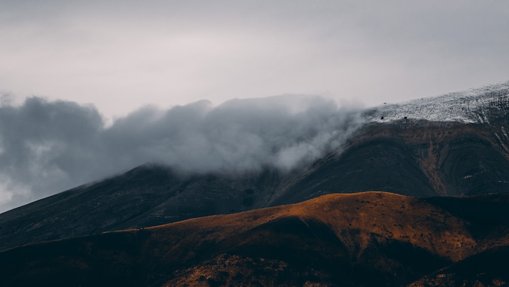 brown and black mountain under white clouds