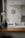 A kitchen interior featuring a modern design with a wooden countertop and a sleek sink. Wall decorations include a larger circular artwork and four smaller plates with artistic designs. An orchid plant and a decorative vase are placed near the window, adding a touch of elegance.