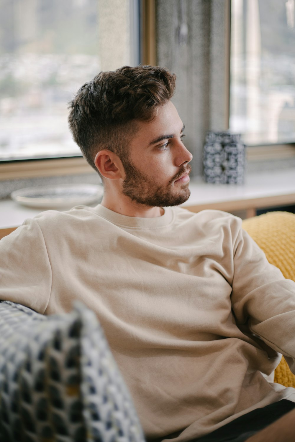 man in white crew neck long sleeve shirt sitting on yellow sofa