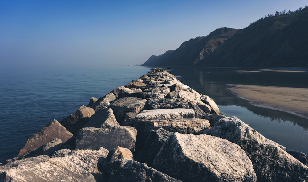 Rivage rocheux gris près d’un plan d’eau pendant la journée