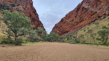 Narrow path between towering red cliffs in Todra Gorge under a bright blue sky