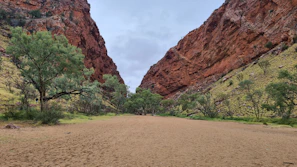 Narrow path between towering red cliffs in Todra Gorge under a bright blue sky