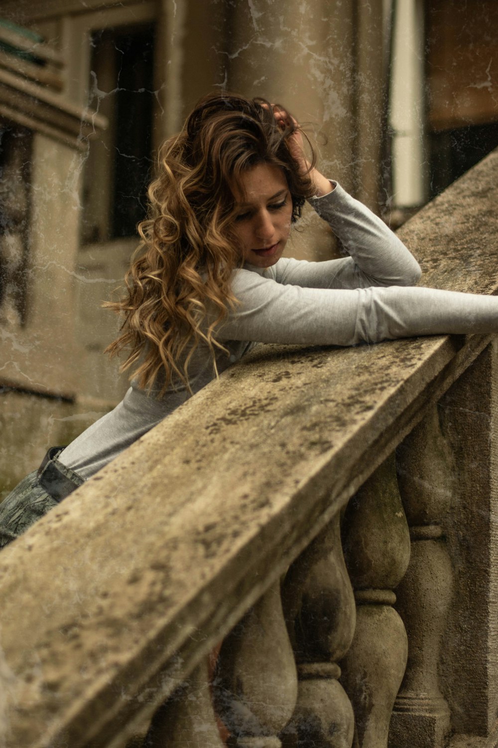 woman in gray long sleeve shirt lying on concrete bench