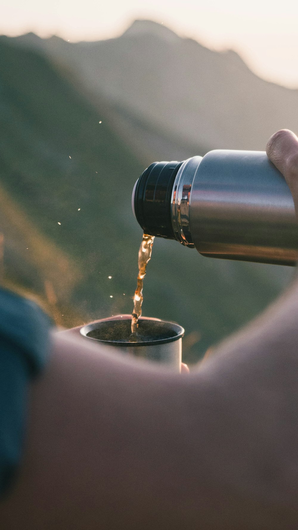 person pouring water on silver and black thermal carafe