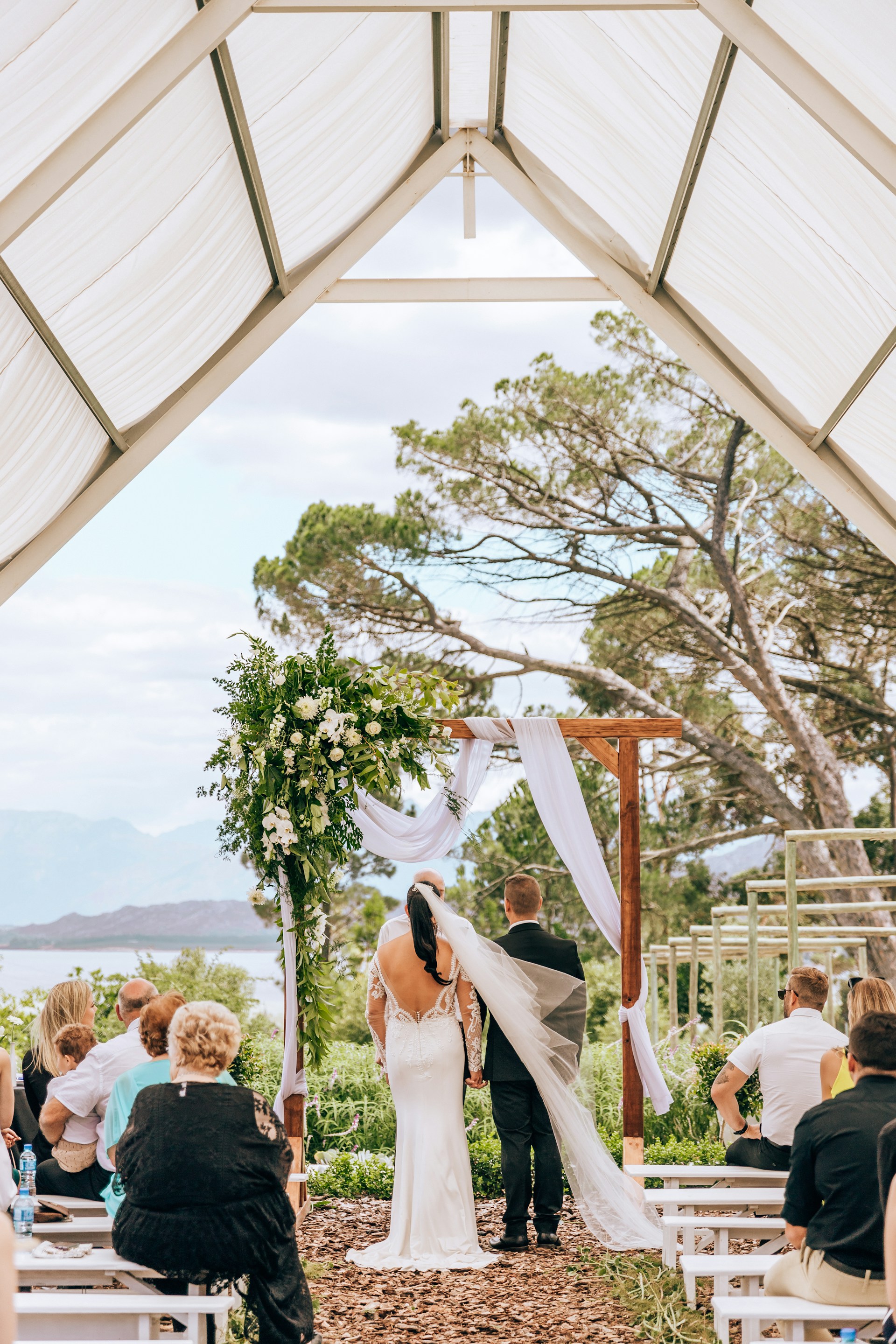 woman in white wedding gown standing on brown wooden canopy tent during daytime