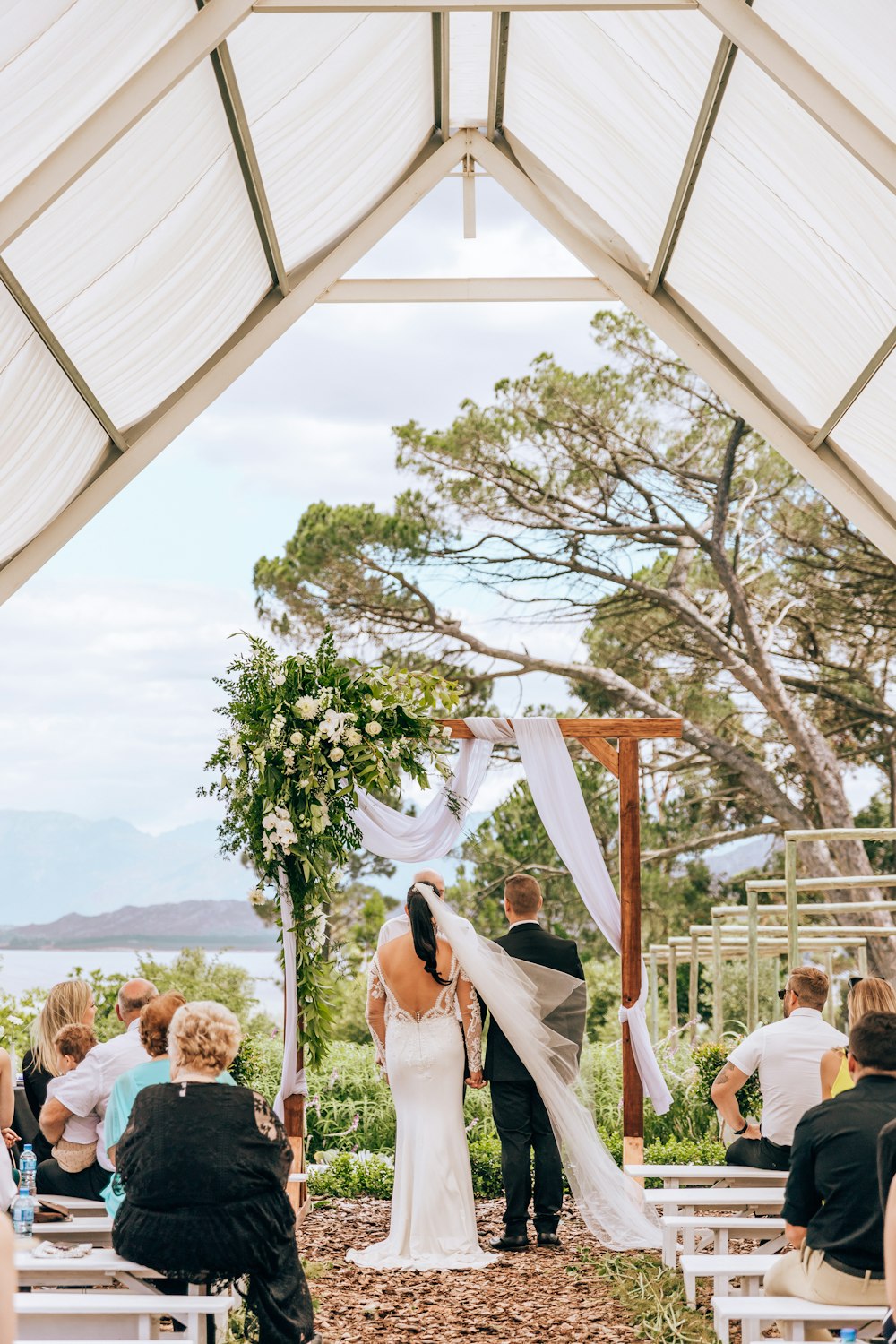 woman in white wedding gown standing on brown wooden canopy tent during daytime