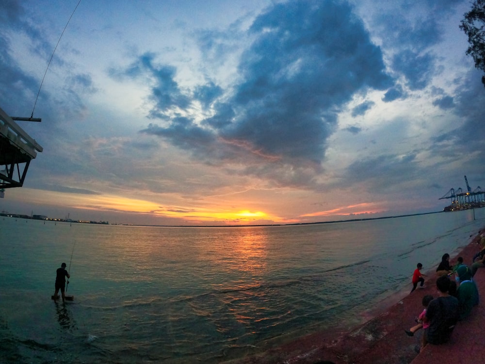 person fishing on sea during sunset