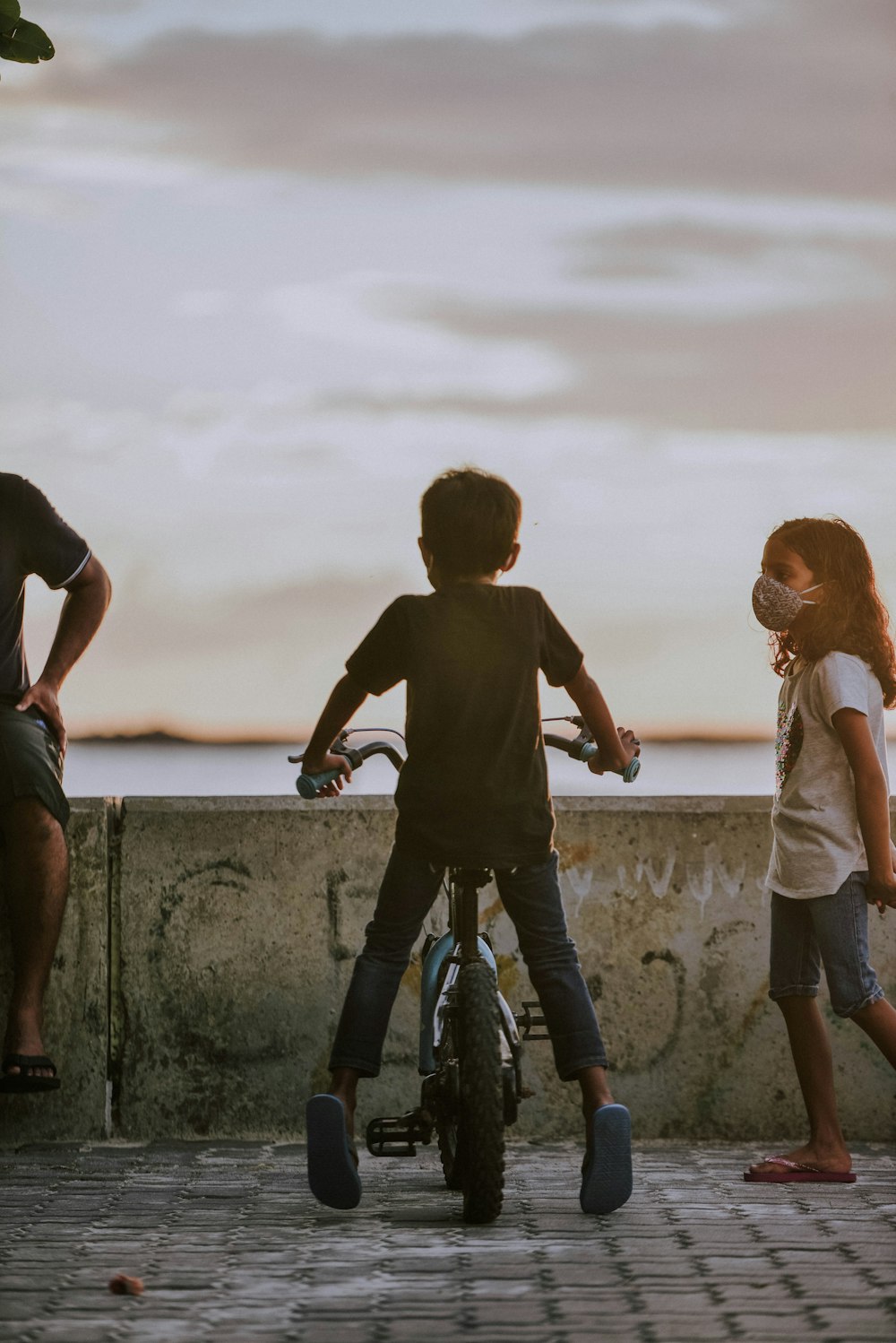 2 boys and girl standing on concrete wall during daytime