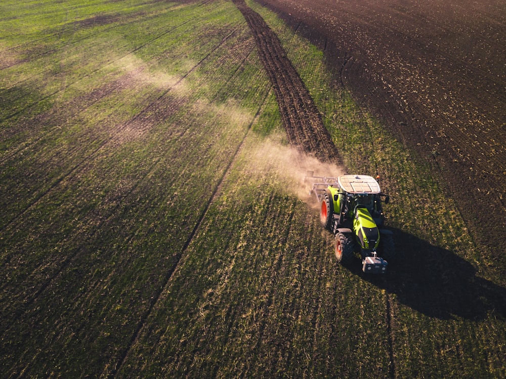 tracteur vert et blanc sur un champ d’herbe verte pendant la journée