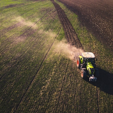 green and white tractor on green grass field during daytime