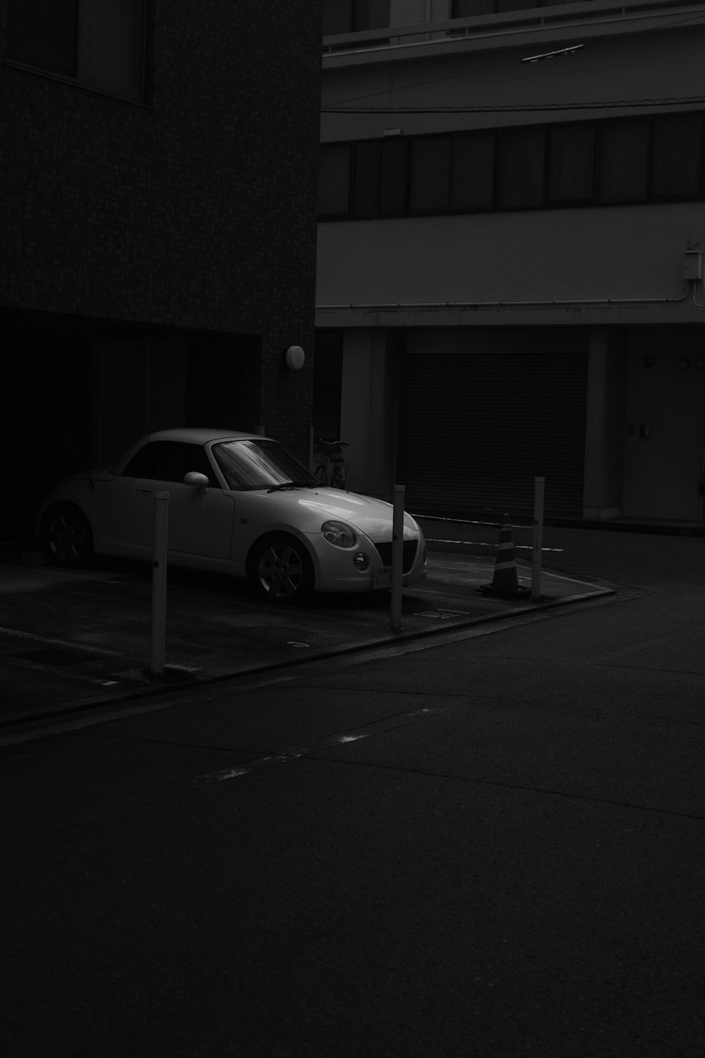 grayscale photo of coupe parked in front of building
