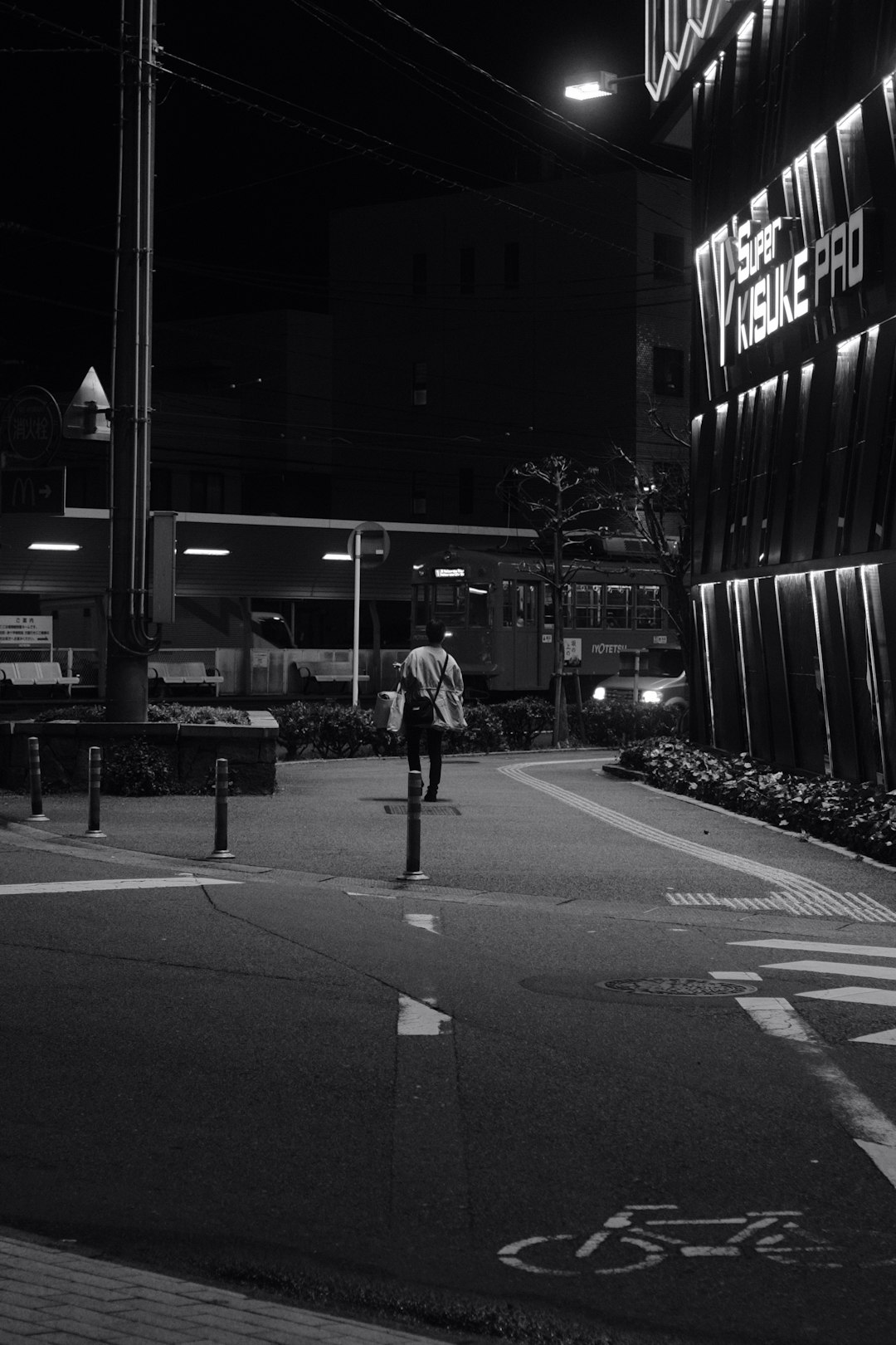 grayscale photo of man walking on sidewalk