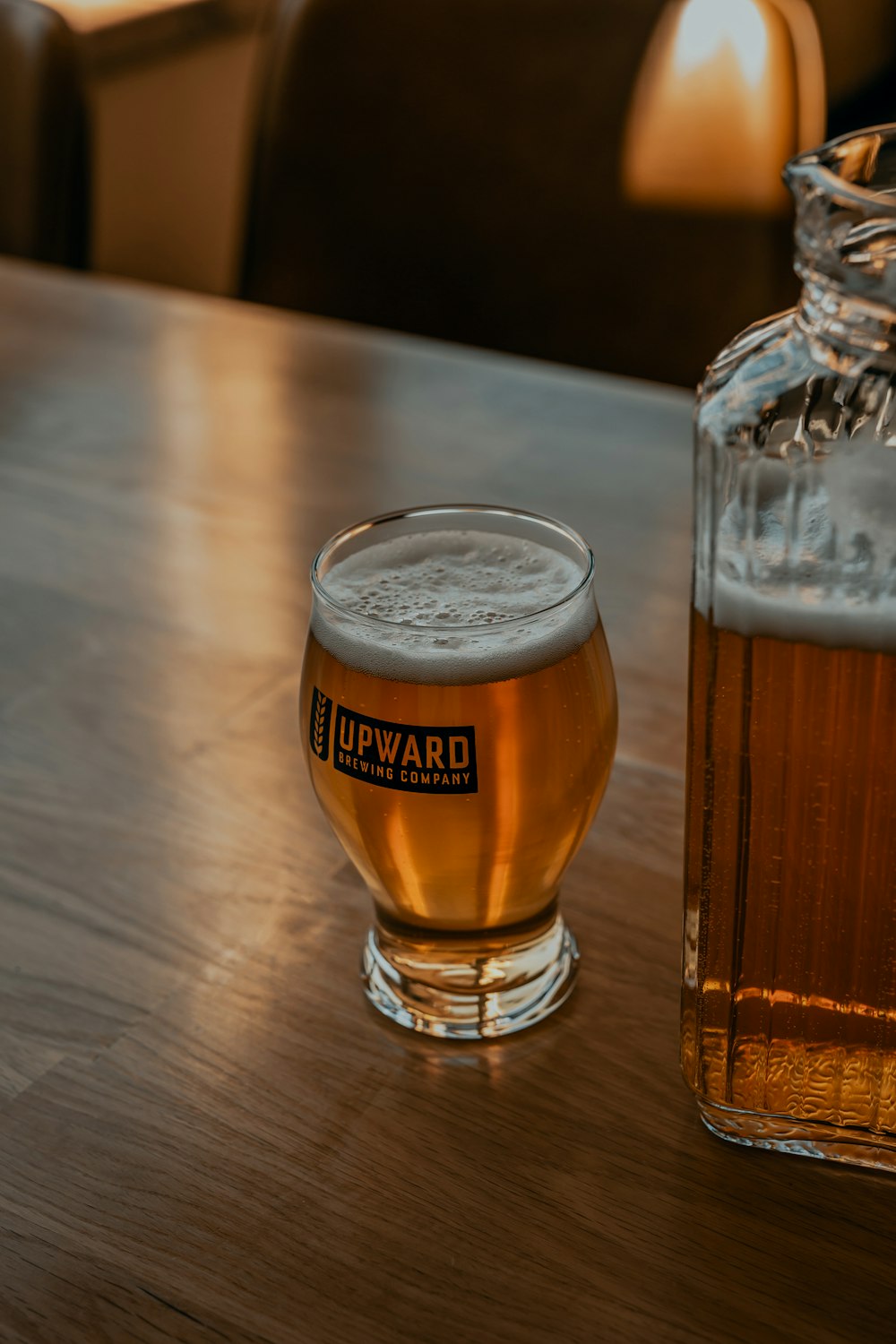 Vaso transparente con cerveza sobre mesa de madera marrón
