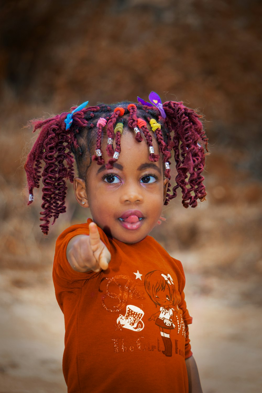 girl in orange crew neck shirt with purple and pink floral headband