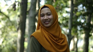 A model wearing a stylish tudung in a cozy outdoor setting with warm sunlight.