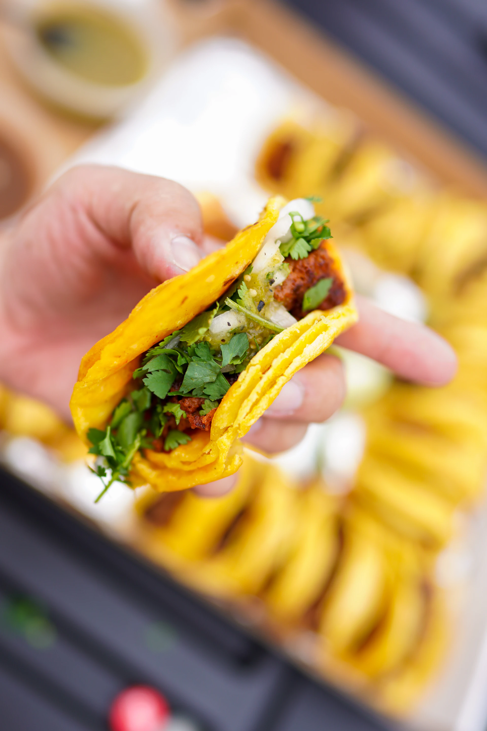 person holding a burger with green vegetable