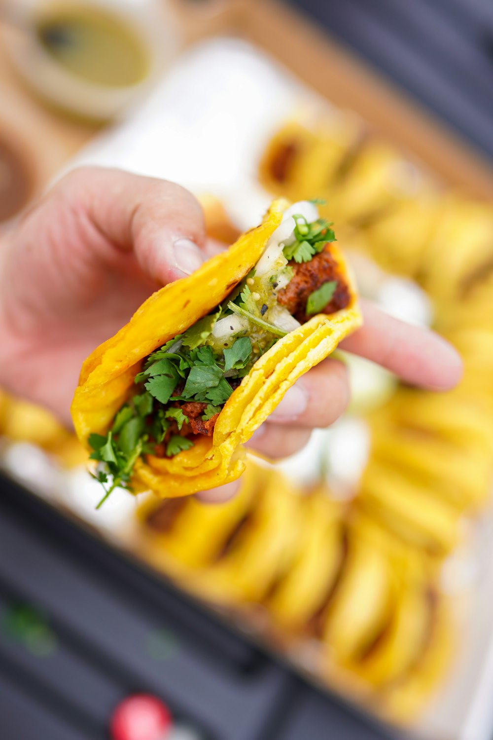 person holding a burger with green vegetable