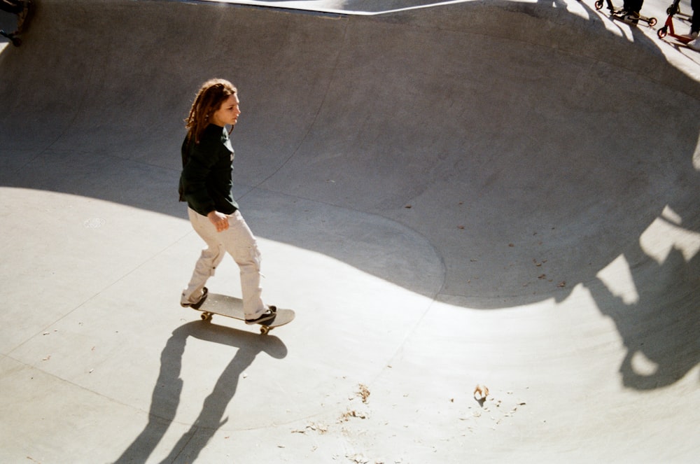 woman in black jacket and white pants walking on white sand during daytime