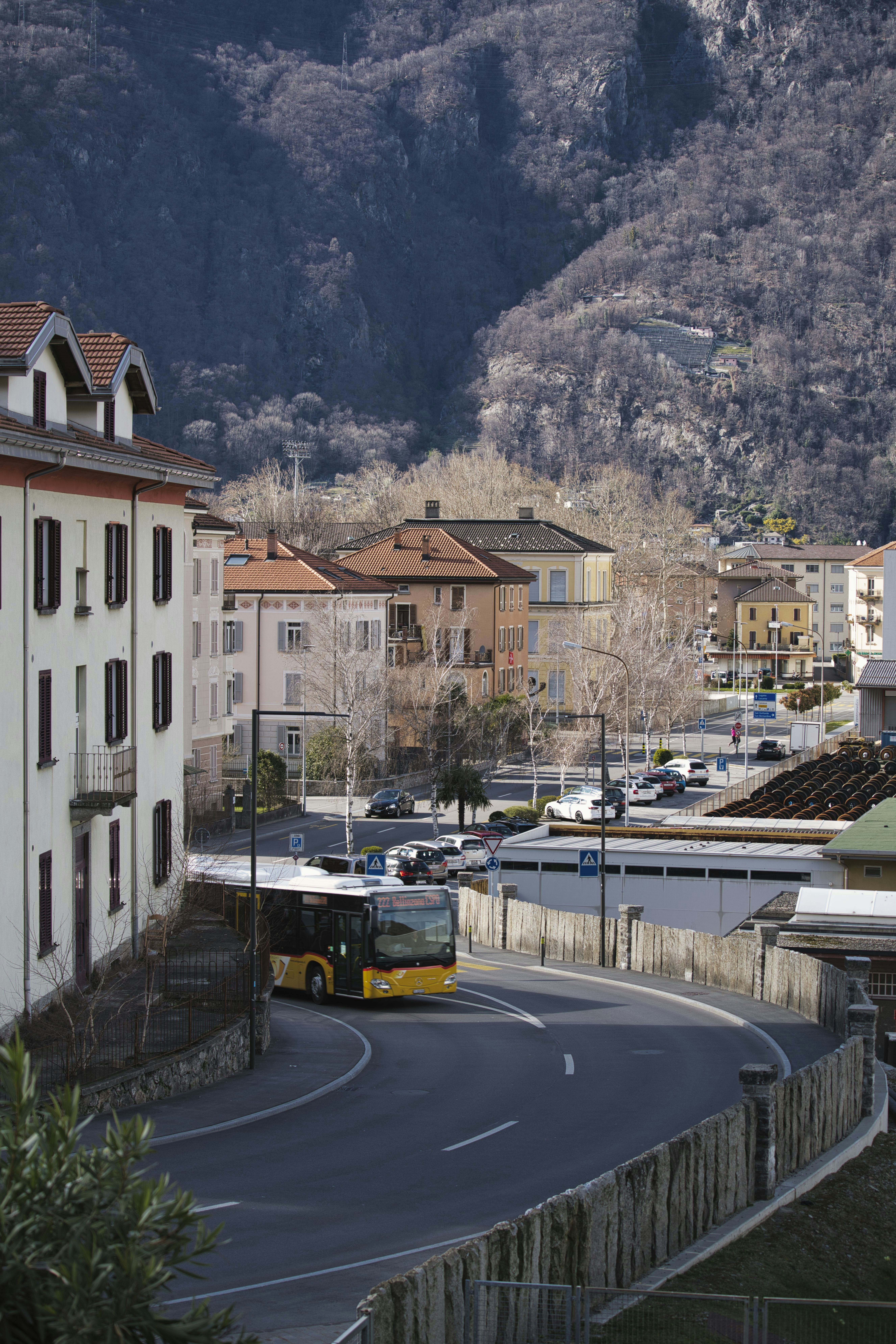 yellow bus on road near white concrete building during daytime