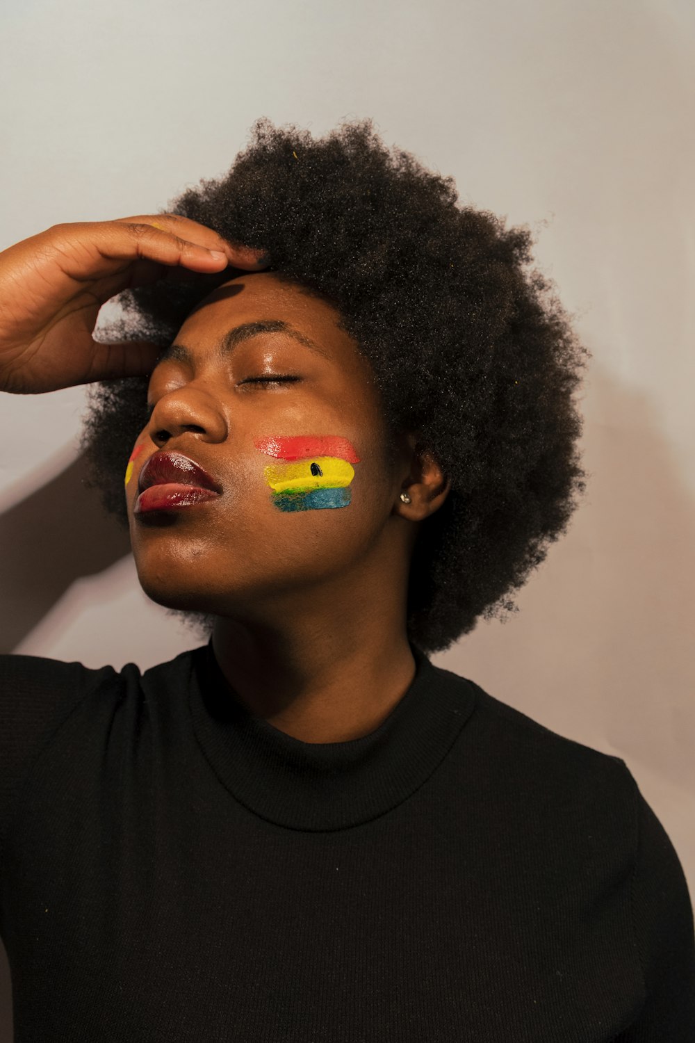 woman in black crew neck shirt with yellow green and red face paint