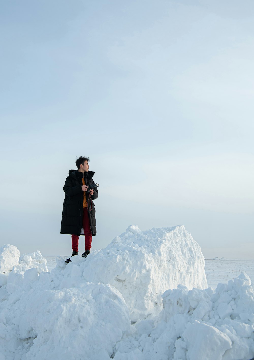 woman in black coat standing on white snow covered mountain during daytime