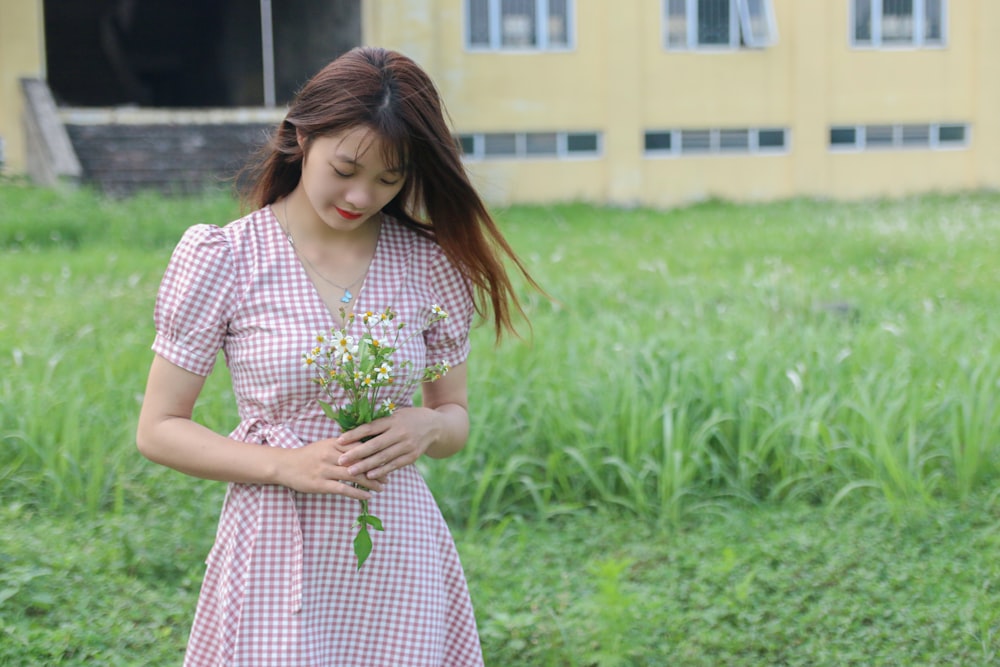 woman in white and red dress standing on green grass field during daytime