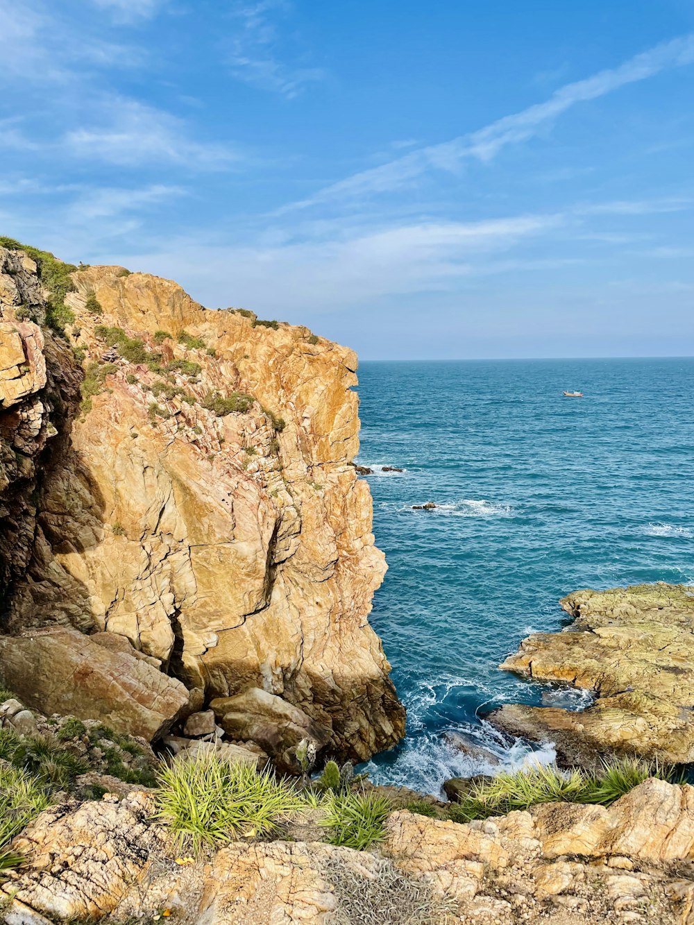 brown rock formation beside blue sea under blue sky during daytime