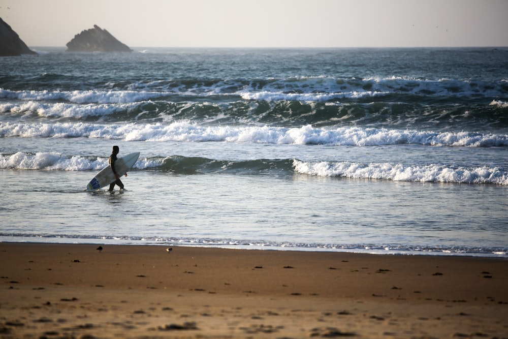 homme en combinaison noire surfant sur les vagues de la mer pendant la journée