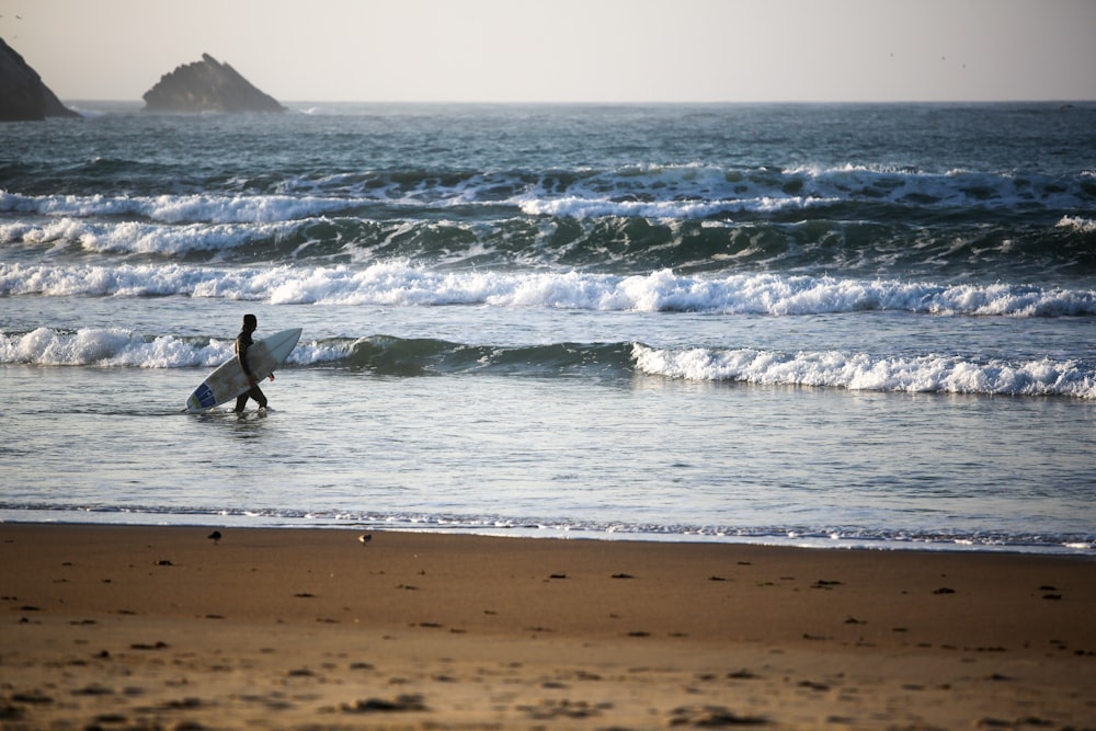 man in black wet suit surfing on sea waves during daytime