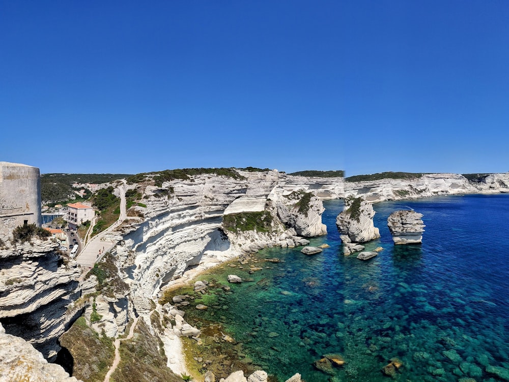 white and gray rock formation near body of water during daytime