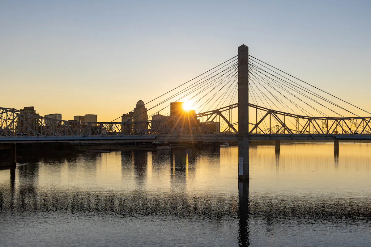 A bridge across the Ohio River with the Louisville skyline at sunset