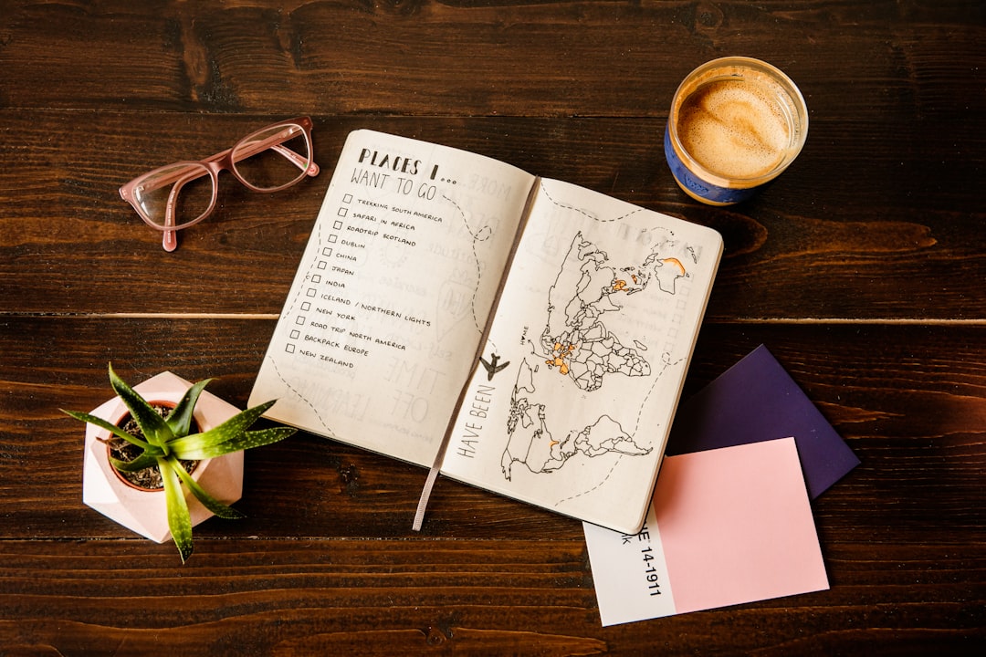 a table with coffee mug, glasses, plant and a book about places I want to go and planning a travel bucket list